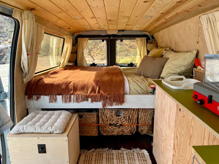 an interior view of a camper van with the bed pulled up and storage drawers open