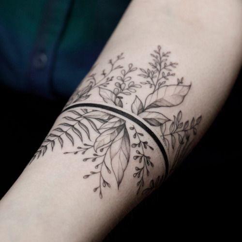 a woman's arm with a black and white tattoo design on the left forearm