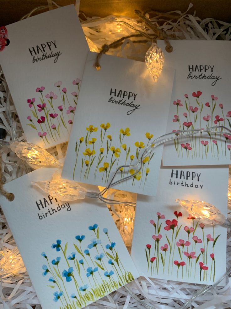 four happy birthday cards in a box with string lights on the side and flowers painted on them