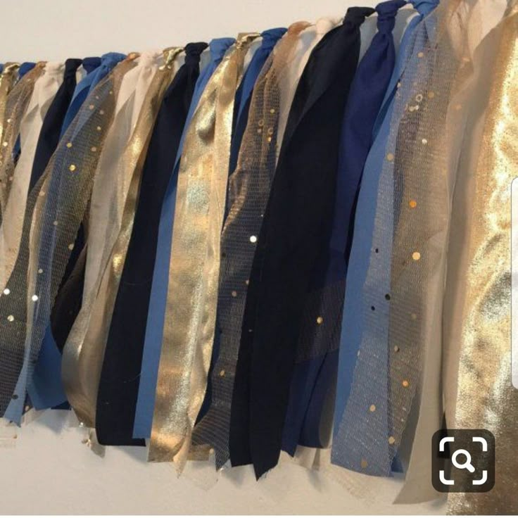 blue and gold ribbons hanging on the wall in front of a white wall with silver sequins