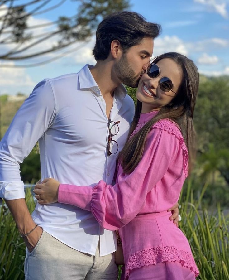 two people standing next to each other with one kissing the other's foreheads