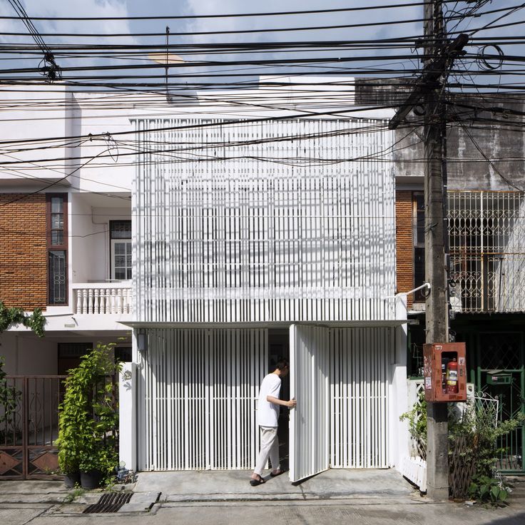 a man standing in the doorway of a building with lots of power lines above it