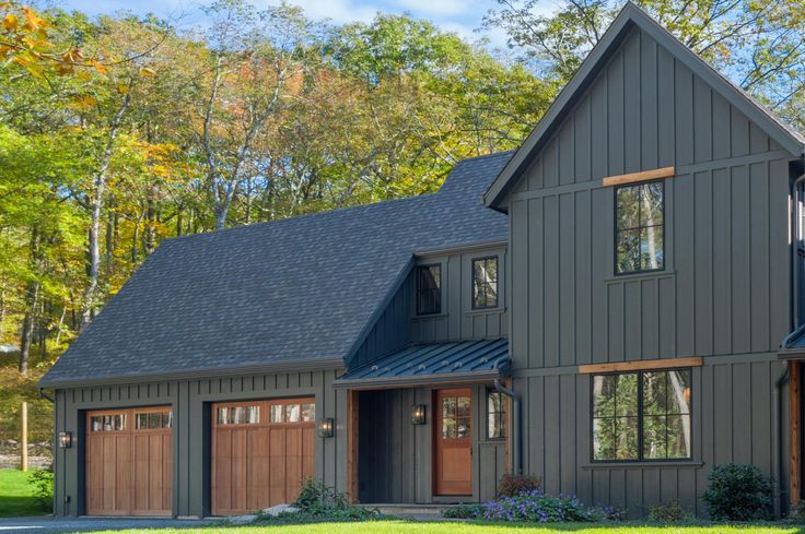 a large gray house with two garages on the front and one story above it