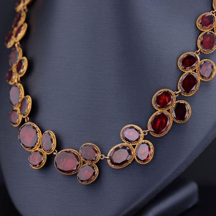 Experience the timeless elegance of this remarkable antique necklace dating back to the late Georgian era (circa 1820). Crafted with meticulous artistry, this exquisite piece showcases 54 oval flat-cut, foil backed garnets, set in 14k bloomed gold with closed backs, preserving their radiance for centuries. Measuring 16 inches in length, this antique necklace exudes a captivating charm and is in overall good condition. While there is one visible surface-reaching inclusion, it adds to the characte 1700s Jewelry, Georgian Necklace, Riviere Necklace, Georgian Era, Garnet Necklace, Antique Necklace, Stylish Jewelry, Gold Gold, Antique Jewelry