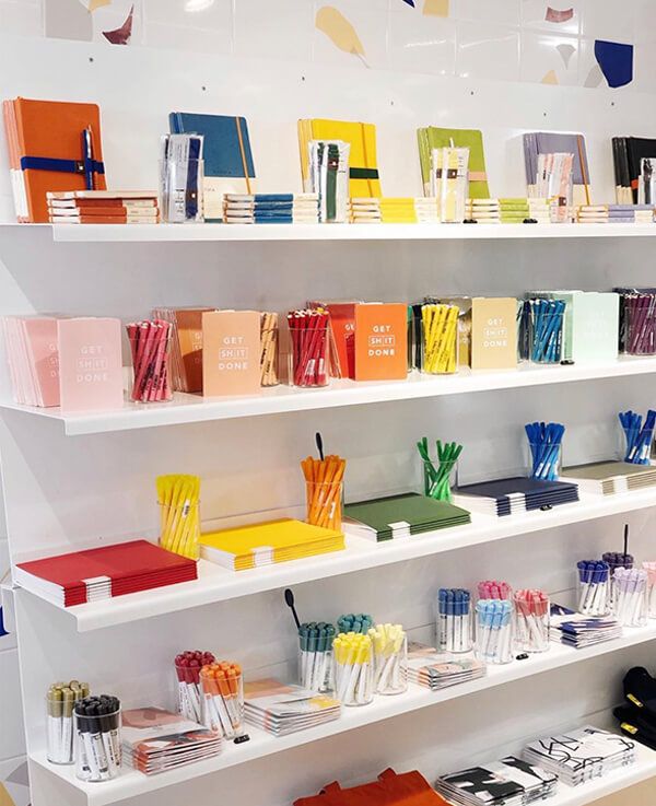 the shelves are filled with many different colored books and stationery pens, pencils and markers