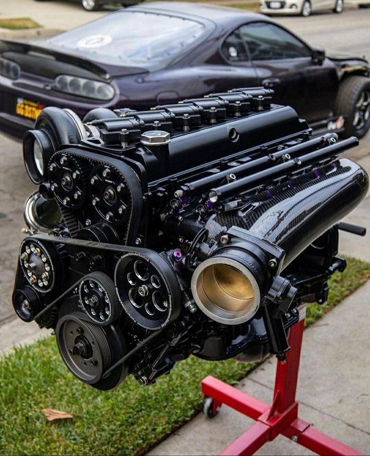 a car engine on a stand in front of a black car and some other cars