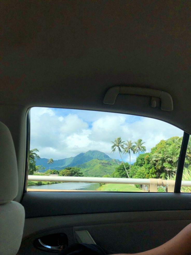 the view from inside a car with mountains in the distance and palm trees on either side