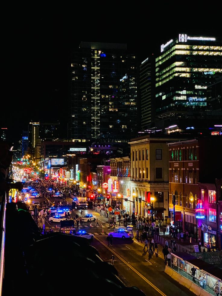 a city street filled with lots of traffic and tall buildings in the background at night