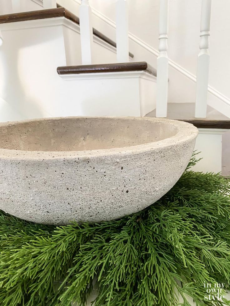 a large stone bowl sitting on top of a green planter in front of a stair case