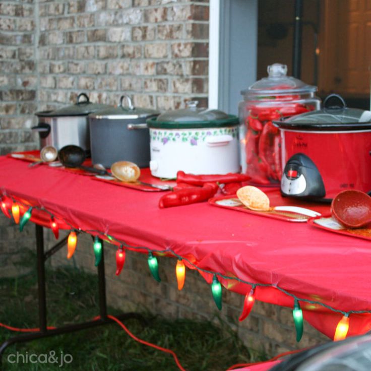 a red table topped with pots and pans filled with food next to a brick wall