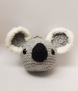 a crocheted koala keychain with a black nose and white ears