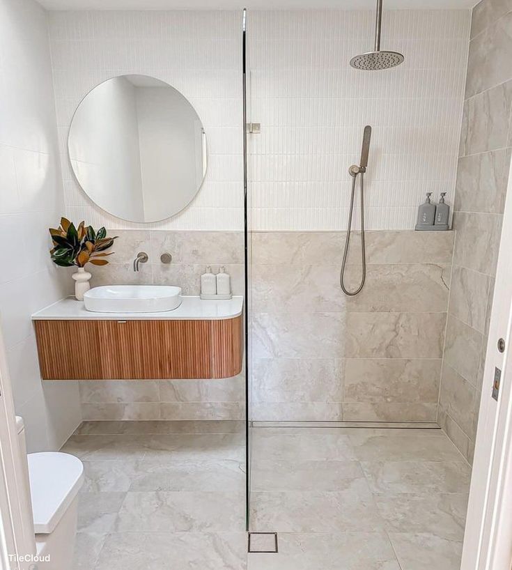 a bathroom with a shower, sink and mirror