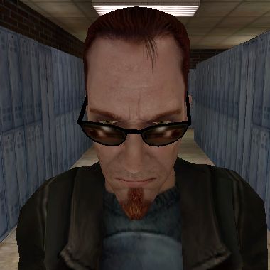 a man with glasses and a beard standing in a hallway next to blue lockers