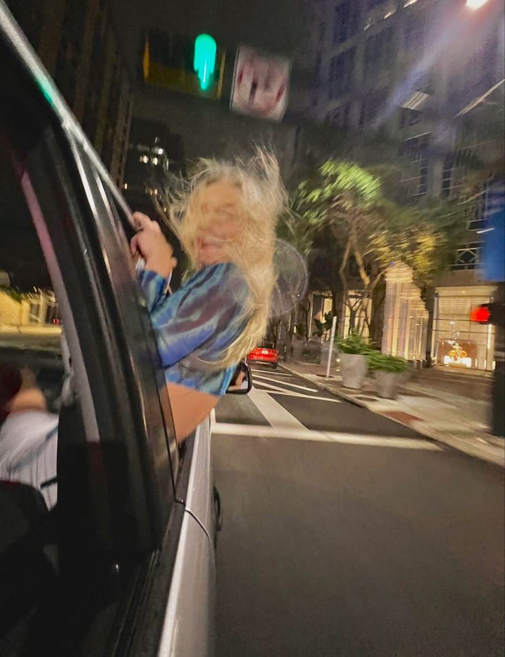 a woman is sitting in the passenger seat of a car and looking at her cell phone