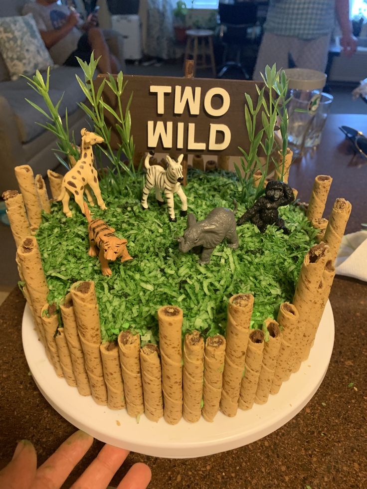 a cake made to look like a jungle scene with animals on the grass and two wild signs