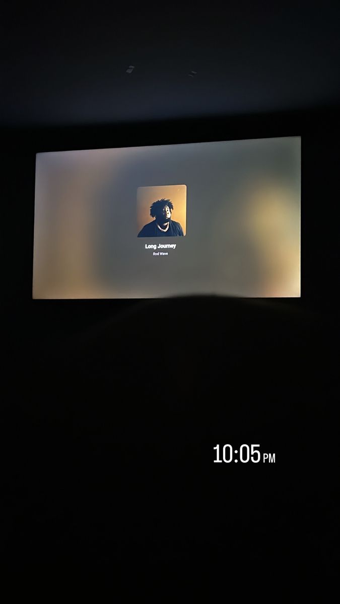 the screen on the wall shows an image of a man with a beard and mustache