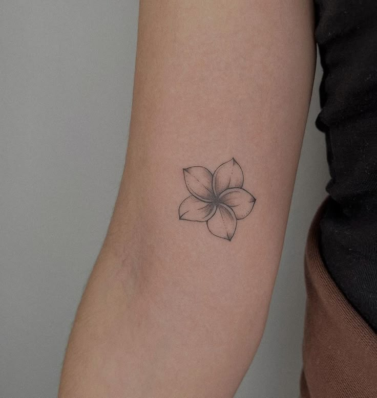 a woman's arm with a small flower tattoo on the left side of her arm