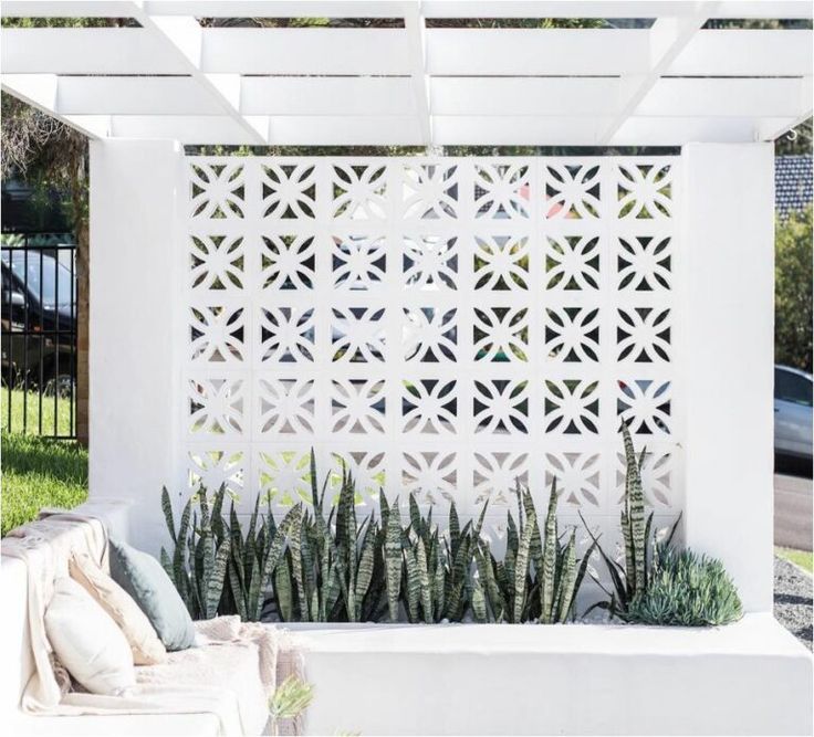 an outdoor living area with white walls and plants on the outside, including succulents