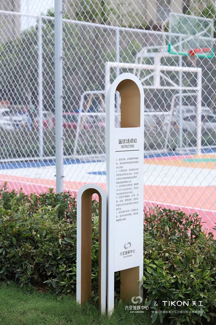 a white sign sitting in the grass next to a fence