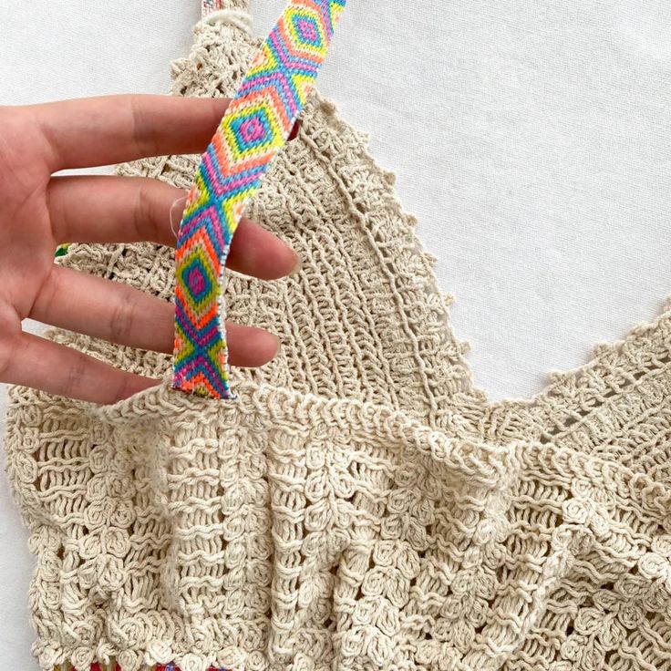 a woman's hand is holding onto a piece of crocheted material that has been made into a dress