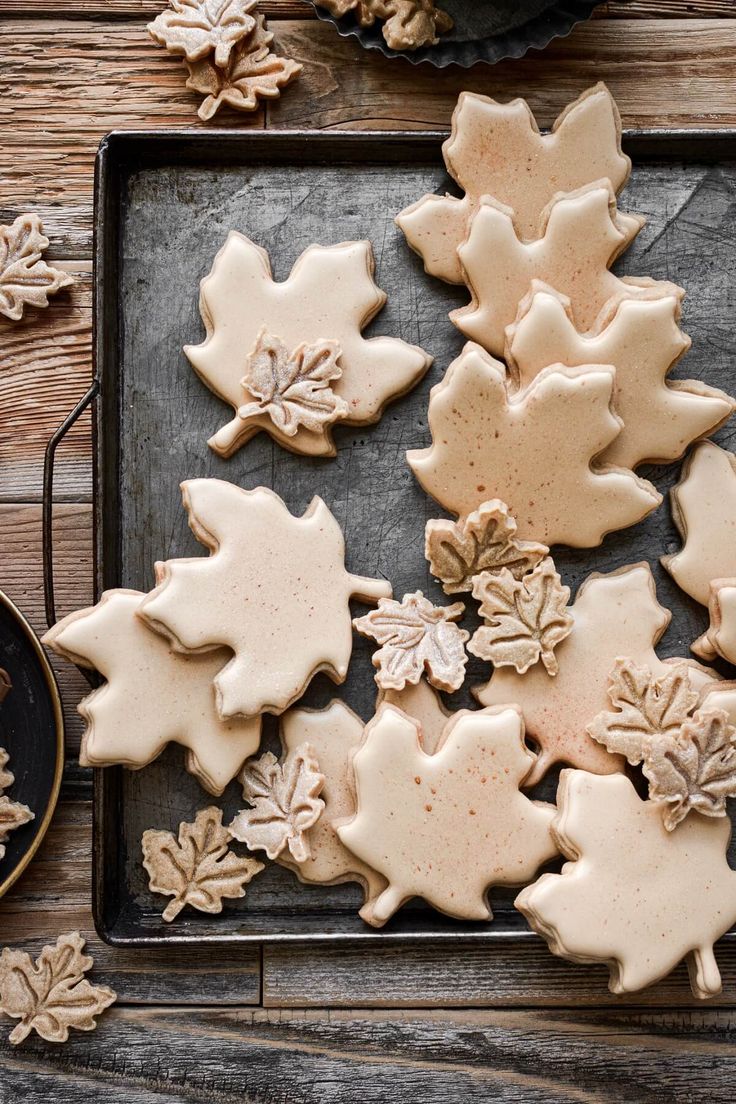 cookies decorated with frosting and leaves are on a tray next to a cup of coffee