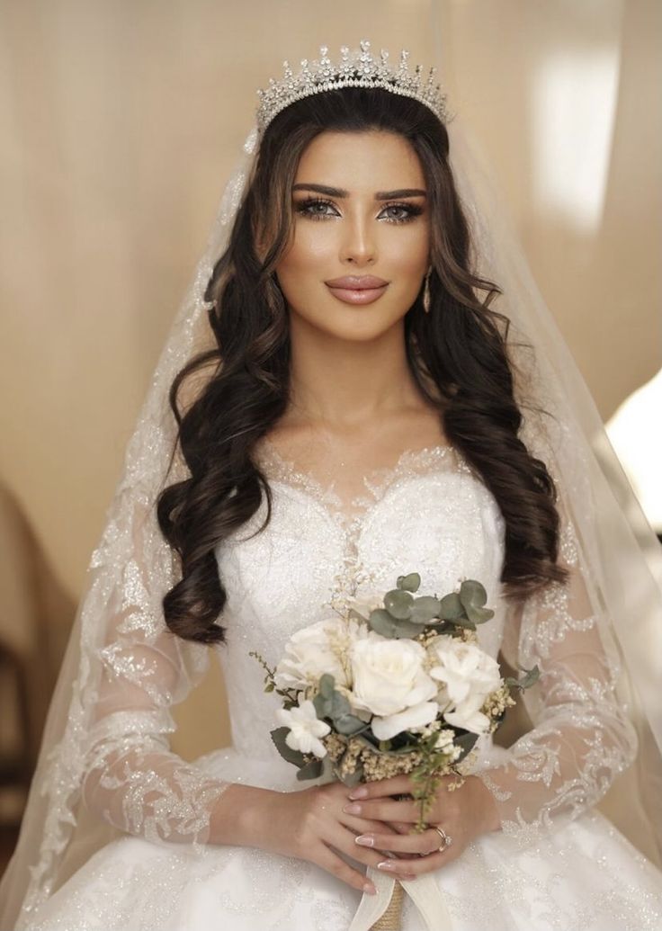 a woman in a wedding dress holding a bridal bouquet and wearing a tiara