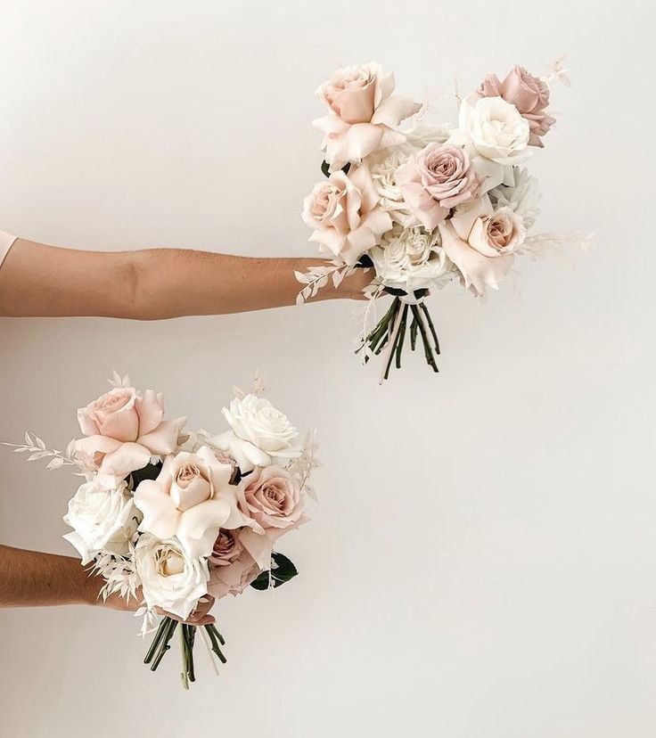 two brides hands holding bouquets of flowers against a white background with copy space