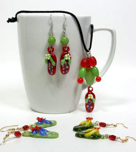 a cup with some earrings on it next to other pieces of jewelry and a mug