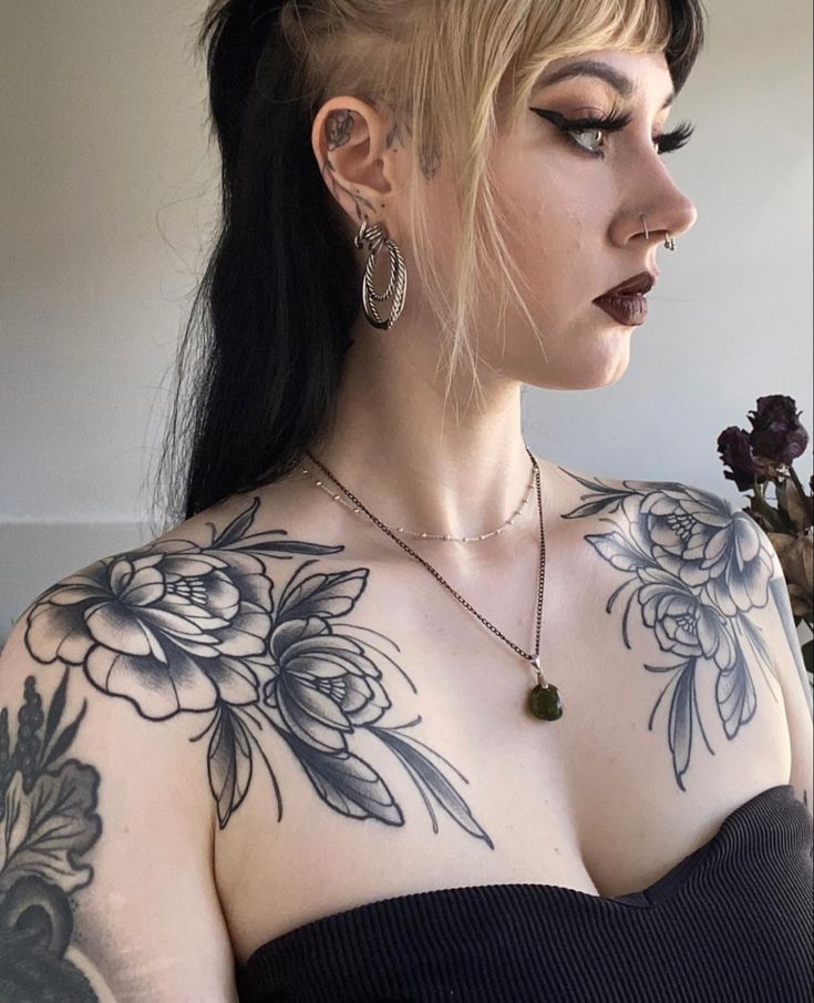 a woman with tattoos on her chest wearing a black dress and holding a flower in her right hand