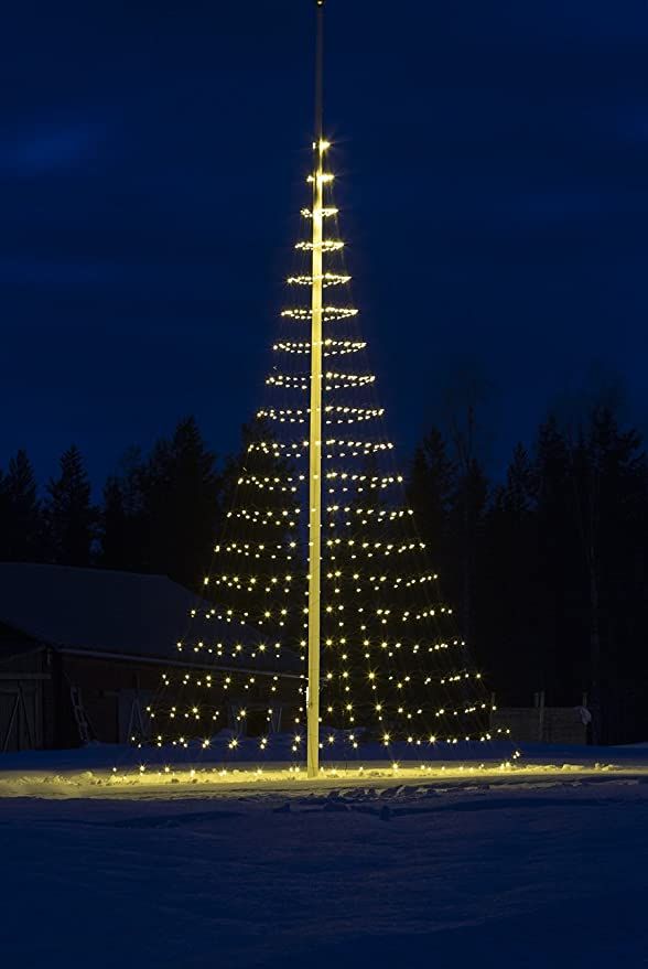 a lighted christmas tree in the middle of a snowy field at night with lights on it