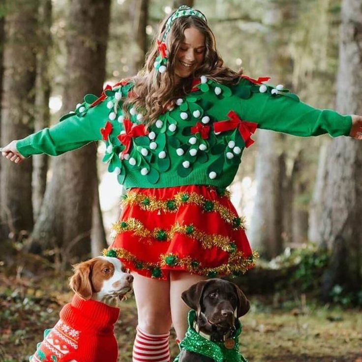 a woman in a christmas sweater and two dogs wearing matching red and green holiday outfits