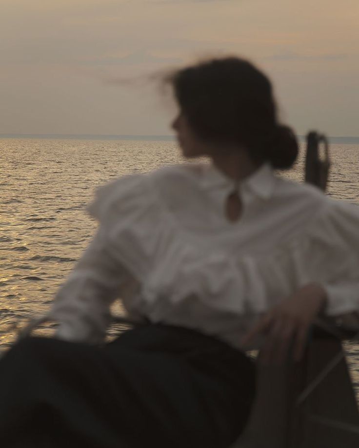 a woman sitting on top of a boat near the ocean