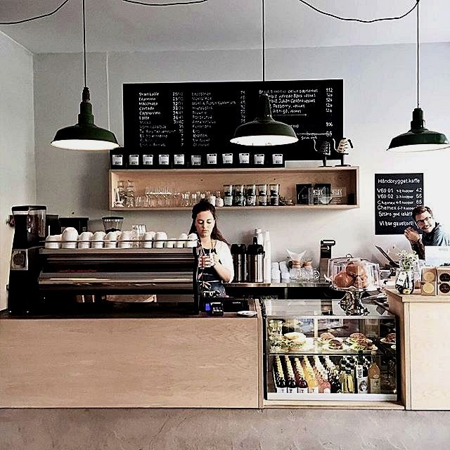 a woman sitting at a counter in a coffee shop next to a man standing behind the counter