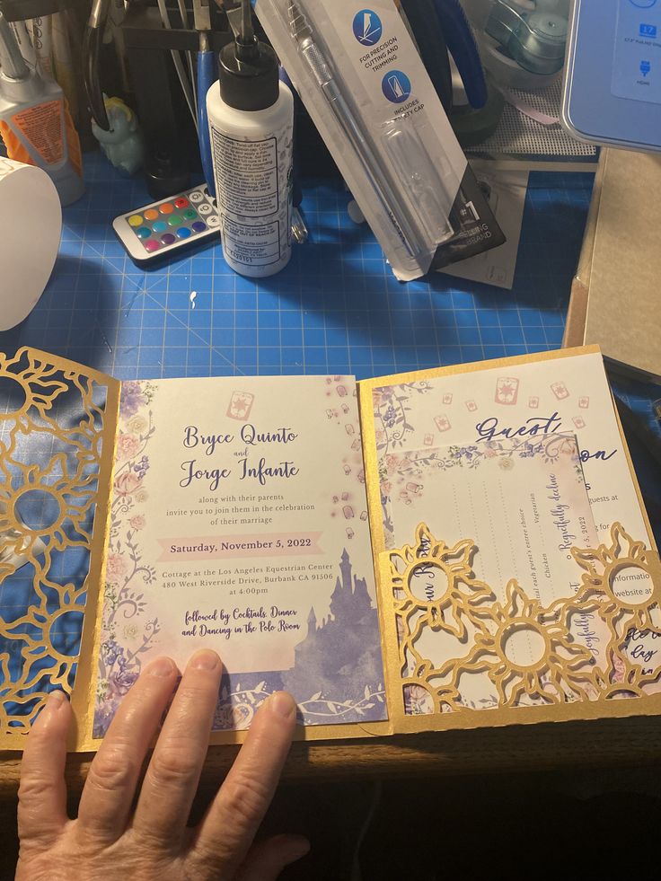 a hand holding an open book on top of a blue table next to other items