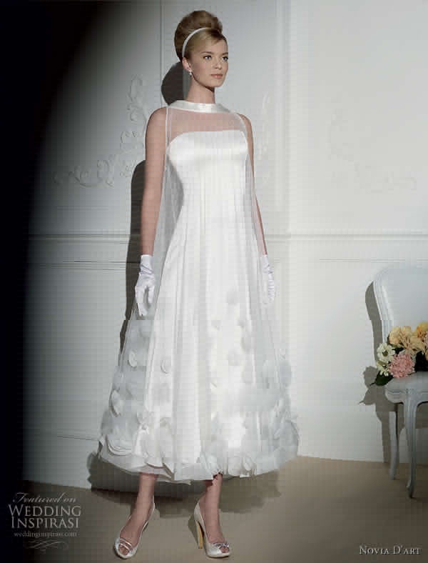 a woman in a white dress and gloves standing next to a chair with flowers on it