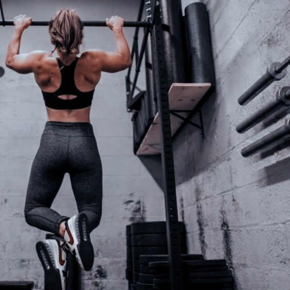 a woman doing pull ups in a gym