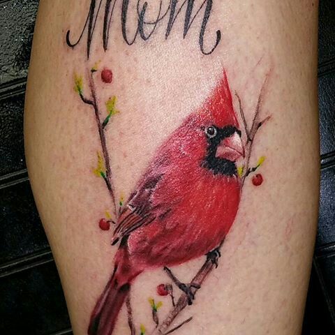 a red bird on a branch with the word mom tattooed on it's leg