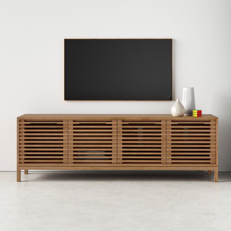 a wooden entertainment center with a blackboard on the wall behind it and vases in front of it