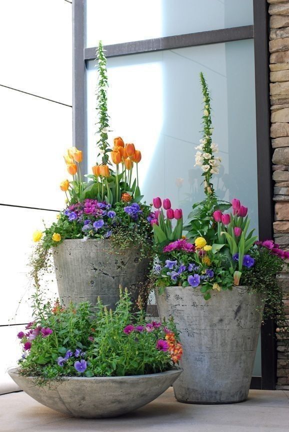 three cement planters filled with colorful flowers