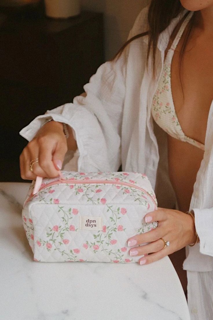 a woman in white shirt sitting at table with pink flowered bag on it's lap