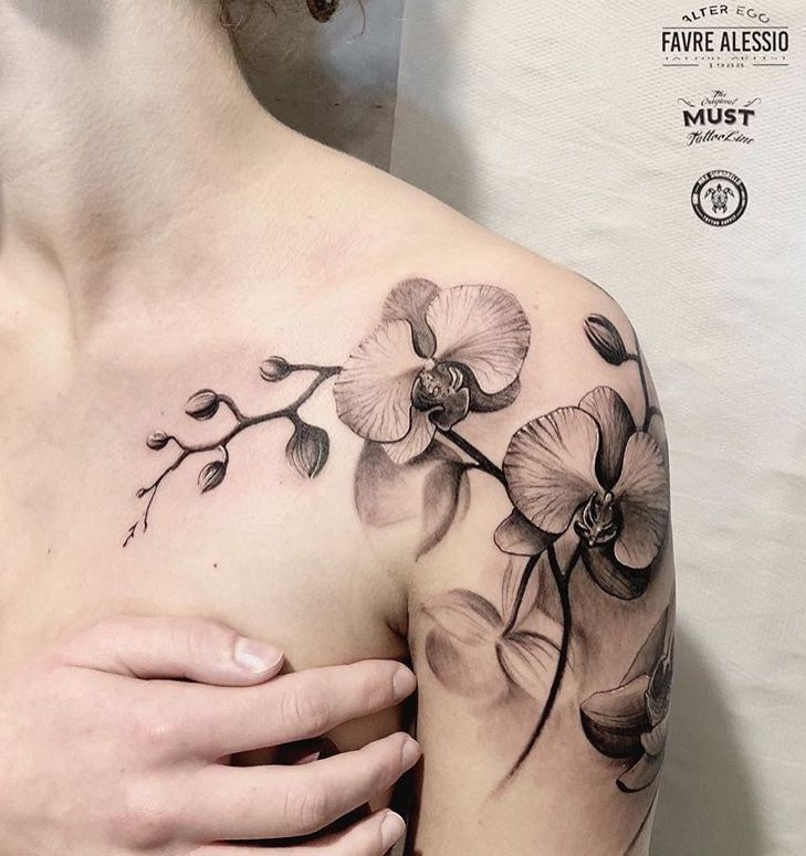 a woman's shoulder with an orchid tattoo on her left arm and the upper half of her body