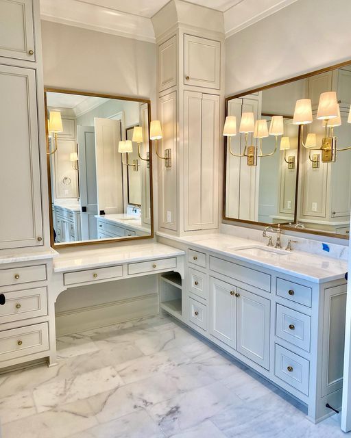 a large bathroom with marble counter tops and white cabinetry, along with two sinks