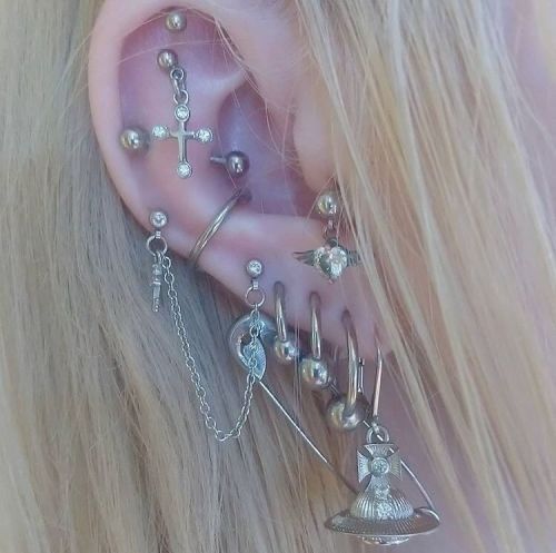 a close up of a person's ear with many different piercings on it