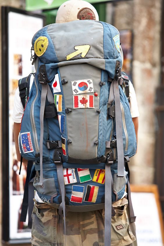 a person with a backpack that has stickers on it and flags on the back