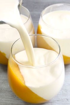 two glasses filled with yogurt sitting on top of a table