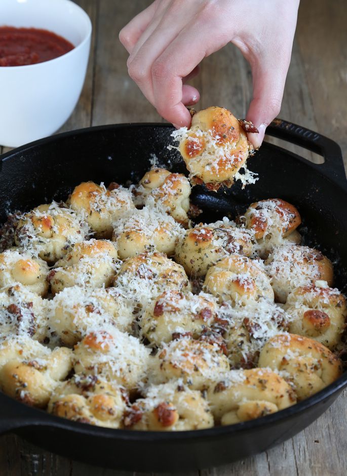 a person scooping some food out of a skillet on top of a wooden table