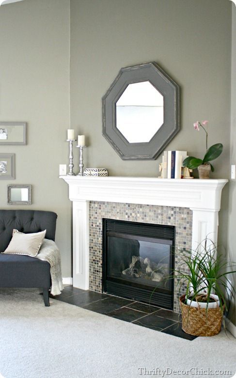 a living room with a fire place and mirror above the fireplace in front of it