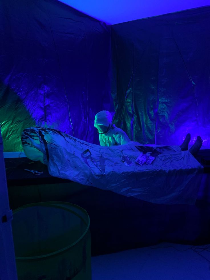 a bed in a dark room with blue lights on the walls and two people laying down