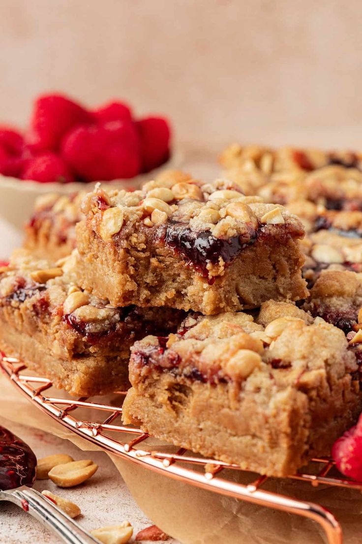 several pieces of cake sitting on top of a cooling rack next to raspberries