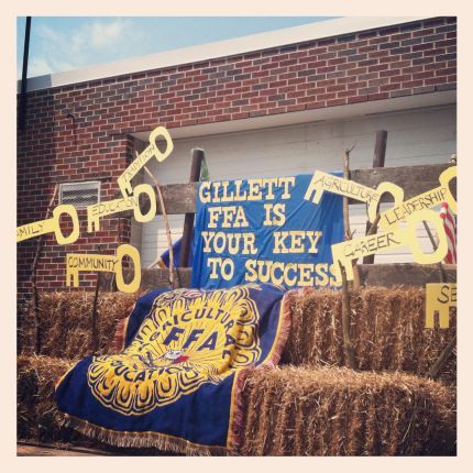 hay bales with signs on them in front of a brick building that says gillet fea is your key to success